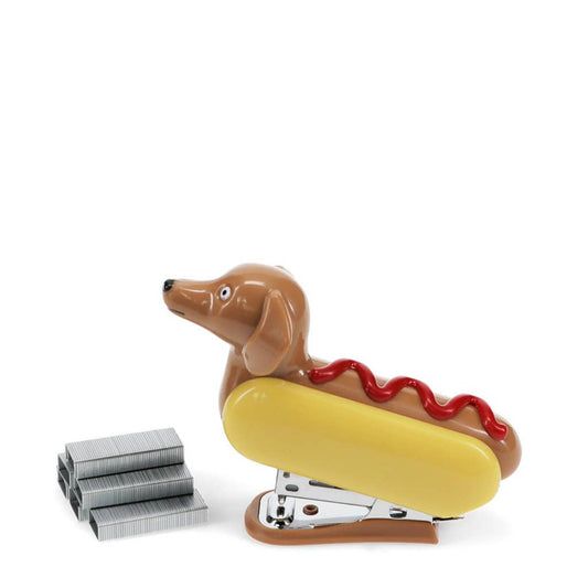 Quirky och nyskapande mini-häftapparat, med en rolig design av en korvhund i ett bröd, med en skvätt ketchup på toppen. En rolig och funktionell kontorsartikel för en hundälskares arbetsplats eller till barnens skrivbord.