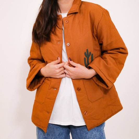 Quiltad jacka med westernmönster med broderad cowboy, häst, kaktusar och moln.
Allt gjort i en cool lappteknik. Här har du en nättare jacka med skjortkrage, knäppning och två fickor. Vi älskar den!