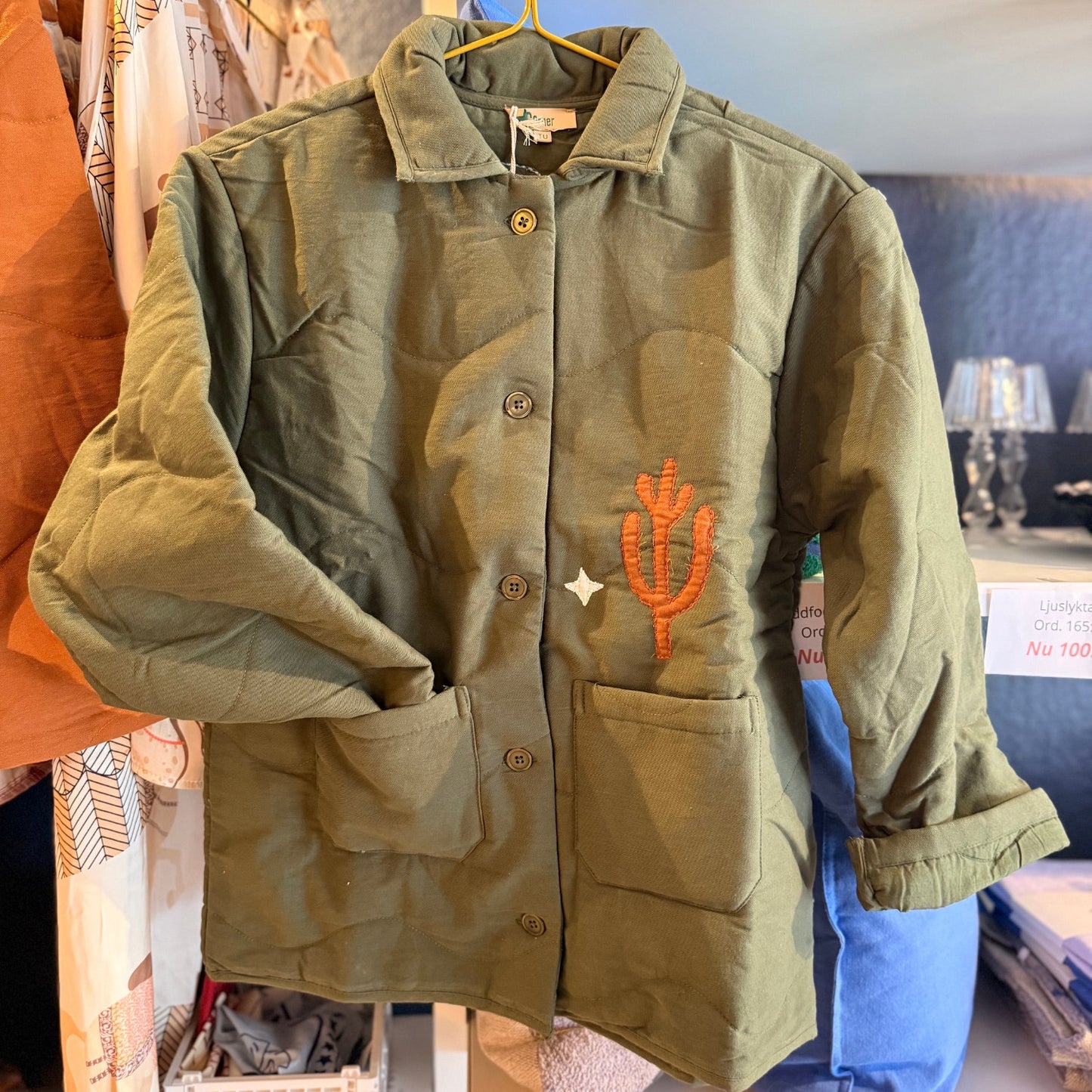 Quiltad jacka med westernmönster med broderad cowboy, häst, kaktusar och moln.
Allt gjort i en cool lappteknik. Här har du en nättare jacka med skjortkrage, knäppning och två fickor. Vi älskar den! The Corner, Paris. Sommarjacka.